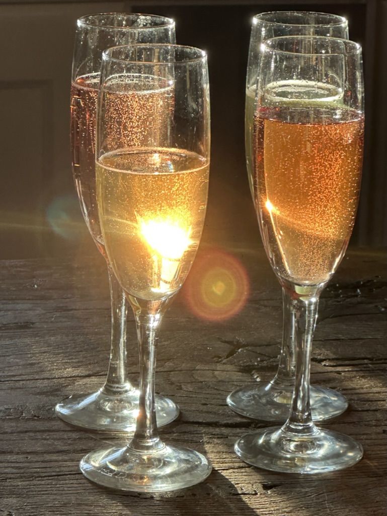 Liqueur de prunelle versée dans des flûtes à champagne, à contre-jour du soleil couchant